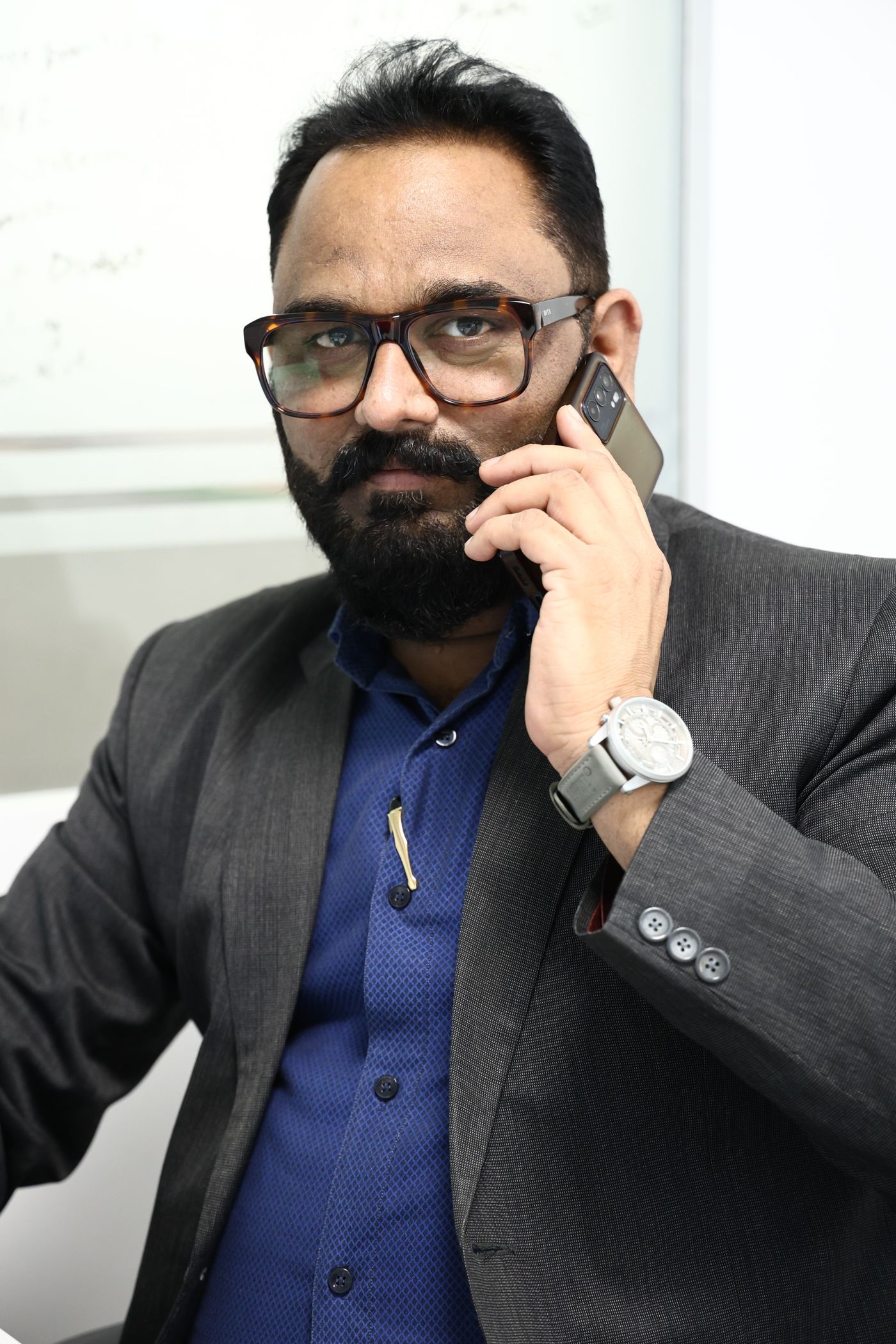 An urban Indian business owner taking a call on his phone